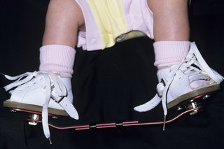 Детски крачета с ботуши, прикрепени към решетката